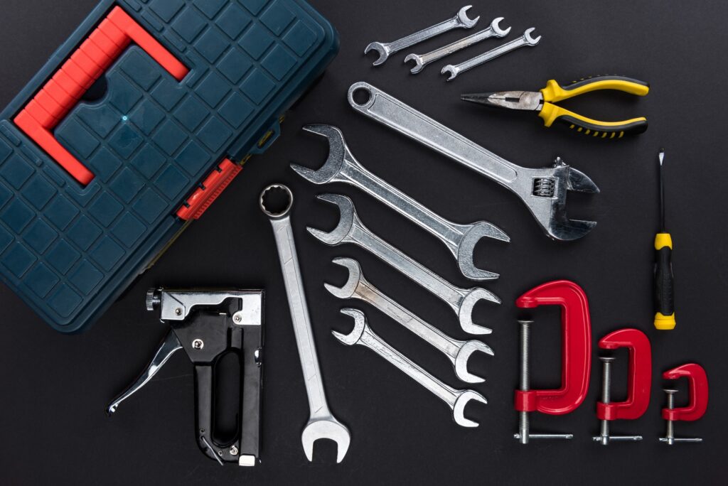 Top view shot of toolbox and various reparement tools on black table top